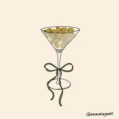 a martini glass filled with olives on top of a white table next to a ribbon