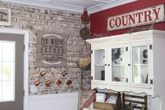 an old fashioned china cabinet in the corner of a room with a country sign above it