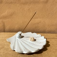 a white shell with a stick in it sitting on a table next to a wall