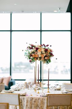 an elegant table setting with tall centerpieces and floral centerpiece in the middle