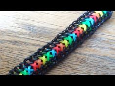 a multicolored bracelet with black chain and metal clasps on top of a wooden table