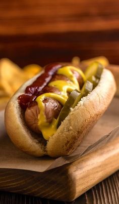 a hot dog with mustard and ketchup on a wooden tray