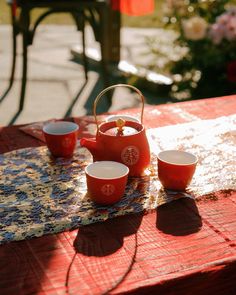 red tea set sitting on top of a wooden table