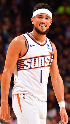 the basketball player is smiling while standing in front of an arena full of people and fans