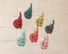 there are many different colored elephant heads on the brick wall and one is black, white, red, blue, green, yellow