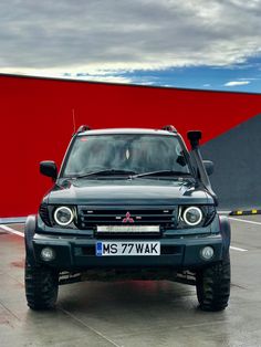 a black truck parked in front of a red wall