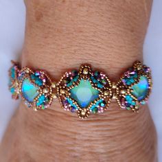 a close up of a person's hand wearing a bracelet with blue and green beads