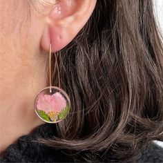 a close up of a person's ear wearing earrings with flowers on them and leaves in the center