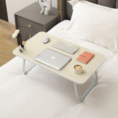 a bed with a laptop, keyboard and mouse on it next to a nightstand table