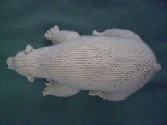 a white knitted fish ornament hanging on a green surface with water in the background