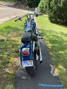 a blue motorcycle parked on the side of a road next to a grass covered field