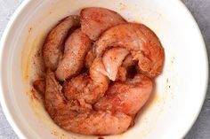 a white bowl filled with cooked meat on top of a table