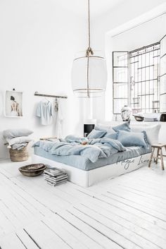 a bedroom with white walls and wooden flooring has a bed made up in light blue linens