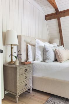 a bed with white linens and pillows in a bedroom next to a wooden dresser