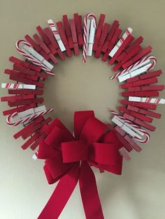 a red and white wreath with candy canes attached to the front, hanging on a wall