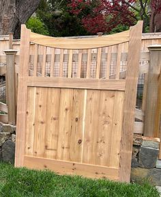 a wooden gate in the grass next to a tree