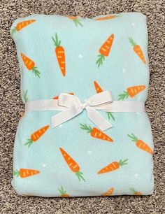 a blue pillow with carrots on it and a white ribbon tied around the corner