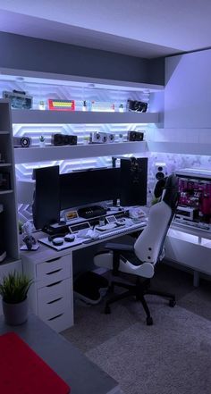 a desk with two computer monitors on top of it next to a shelf filled with electronics