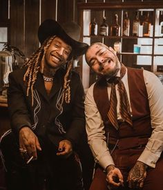 two men sitting next to each other in front of a bar