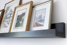 three framed pictures are hanging on a shelf