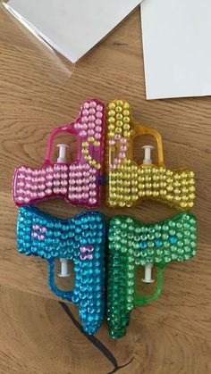 four different colored plastic bows on a wooden table