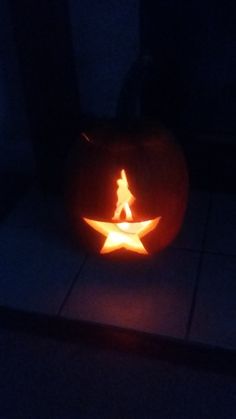 a pumpkin carved to look like a person walking on a star is lit up in the dark