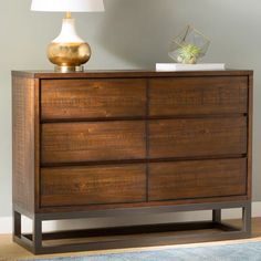 a wooden dresser with a lamp on top of it