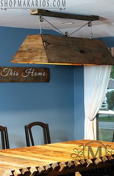 a wooden table with chairs and a light hanging from the ceiling in a dining room