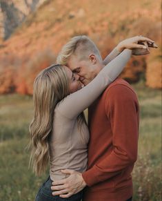 a man and woman embracing each other in front of a mountain with mountains behind them