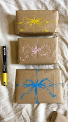 three wrapped presents are sitting on a bed next to a pen and paper with blue ink