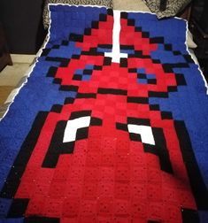 a bed with a red and blue bedspread that has an image of spiderman on it