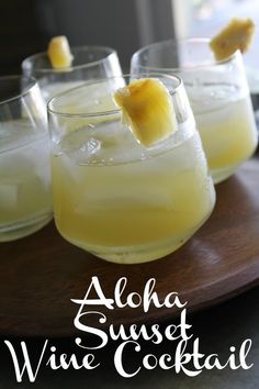 three glasses filled with alcohol sitting on top of a wooden tray covered in pineapple slices