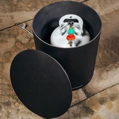 a black bucket with a white and red object in it sitting on the ground next to another container