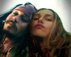 a man with long hair hugging a woman's face while she is dressed as captain jack sparrow