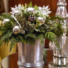 a silver vase filled with christmas decorations on top of a table