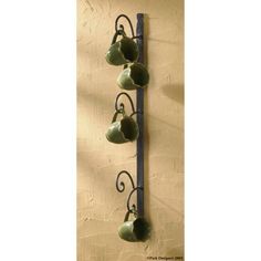 a wall mounted tea pot rack with five cups hanging from it's sides,