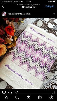 a white and purple towel sitting on top of a lace covered table cloth next to flowers