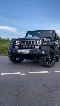 a black jeep is parked on the side of the road in front of some bushes