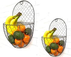 two metal baskets filled with fruit on top of a white wall