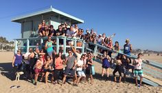 a group of people standing on top of a beach next to a life guard tower