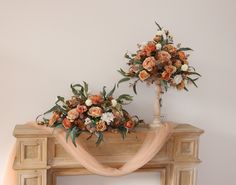 two vases filled with flowers on top of a wooden fireplace mantel next to a white wall