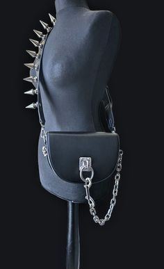 This is a goth/ punk rock style shoulder crossbody bag. Made with premium quality pu leather and aluminium 44mm tree spikes and  attachments with large O ring in the centre with chunky aluminium chain attachment. Studded with pure white brass cast skulls on both sides . Comes with a very eye catching fully studded with 44mm tree spikes bag strap / belt Strap total length is 42 to 46 inches adjustable strap with buckle.  Main material: Pu leather ( vegan leather) Lining material: ,polyester  Clos Punk Purse, Punk Bag, Goth Bag, Accessories Design Sketch, Goth Purse, Spike Bag, Punk Rock Style, Gothic Bag, Handmade Belt