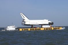 the space shuttle is being transported by a tug boat in the middle of the ocean