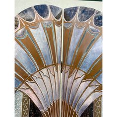 an art deco fan is shown in front of a white wall with blue and gold designs