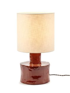 a brown table lamp with a white shade on the base and a cord attached to it