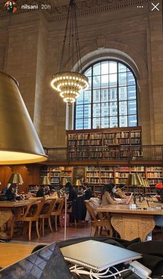 a large library filled with lots of books and people sitting at tables next to each other