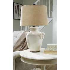 a table with a lamp on top of it next to a couch and stairs in the background