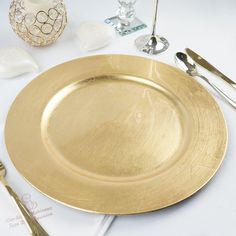 a gold plate sitting on top of a table next to utensils and silverware