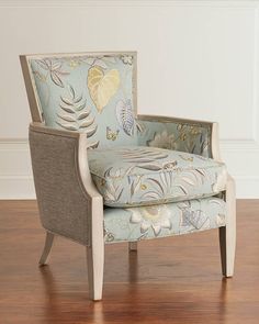 an upholstered chair with blue and white floral fabric on the armrests