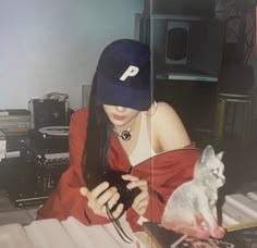 a woman sitting on the floor looking at her cell phone while wearing a hat and holding a camera